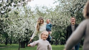 A joyful family enjoys a playful day outdoors amidst blossoming trees in spring.